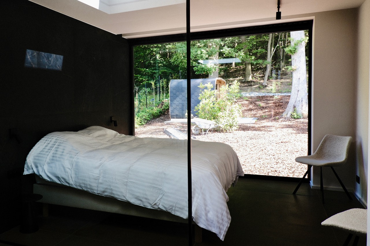 Chambre avec grand lit et baie vitrée donnant sur la forêt au gîte Cit'Art