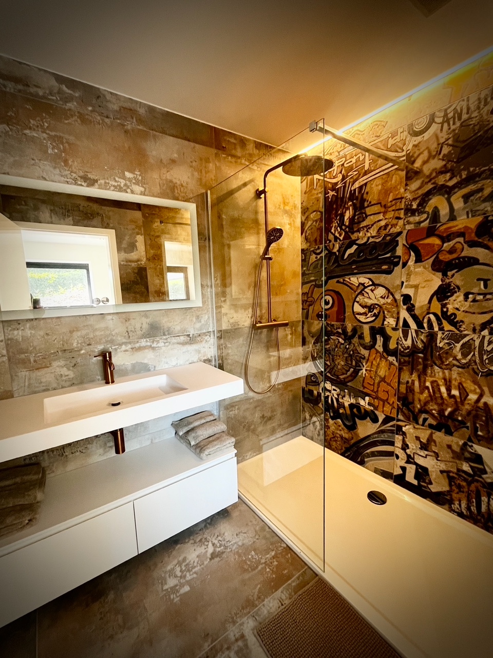 Salle de bain avec douche à l'italienne et mur graffiti au gîte Cit'Art